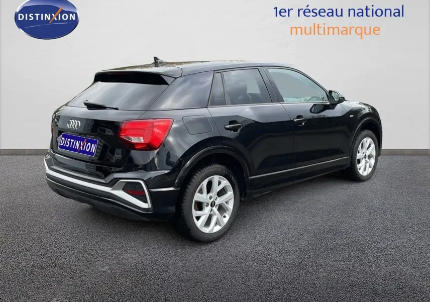 Audi Q2 noir mito metal vue 3/4 arrière droit, mettant en valeur ses feux arrière rouges et jantes argentées.