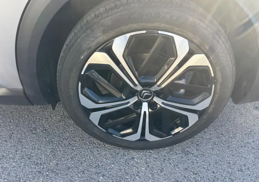 Gros plan sur la jante alliage 19 pouces noire et argentée d'une Citroën C5 X gris foncé, côté avant droit.