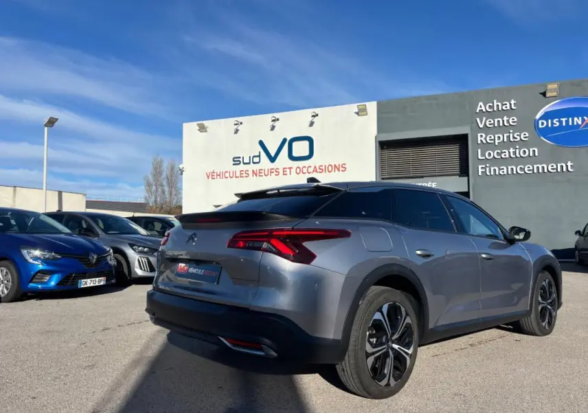 Vue 3/4 arrière droite d'une Citroën C5 X gris foncé avec jantes alliage 19 pouces, barres de toit et vitres teintées.