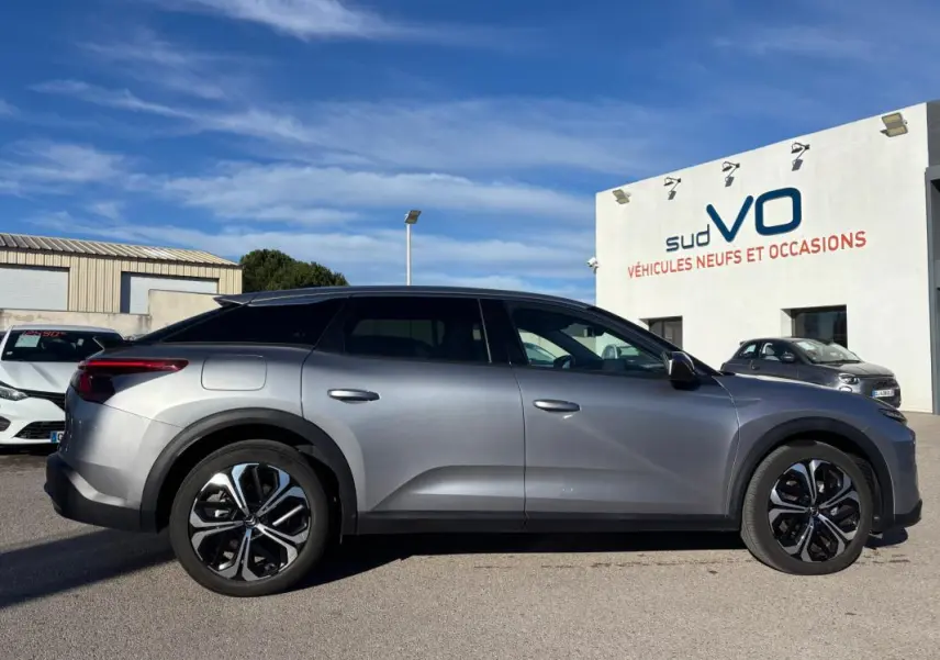 Vue de profil côté gauche d'une Citroën C5 X gris foncé 2024 avec jantes alliage 19 pouces et toit noir.