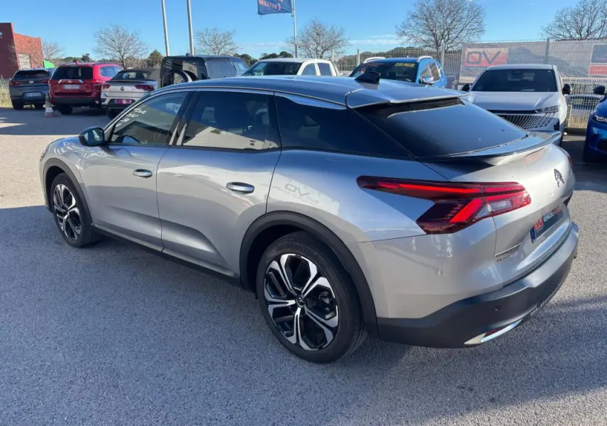 Vue 3/4 arrière droite d'une Citroën C5 X gris foncé avec jantes alliage 19 pouces et toit noir brillant.