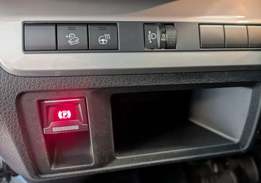 Gros plan sur la console intérieure du fourgon Opel Vivaro XL blanc, montrant les boutons de contrôle et le frein à main électronique allumé.