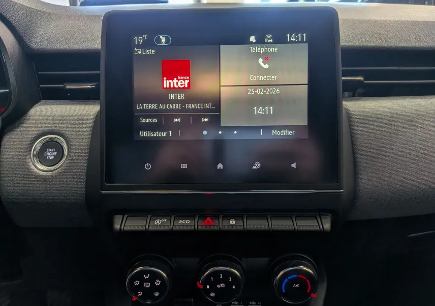 Vue rapprochée de l’écran tactile central et des commandes de climatisation de la Renault Clio V Bleu Iron, intérieur noir.