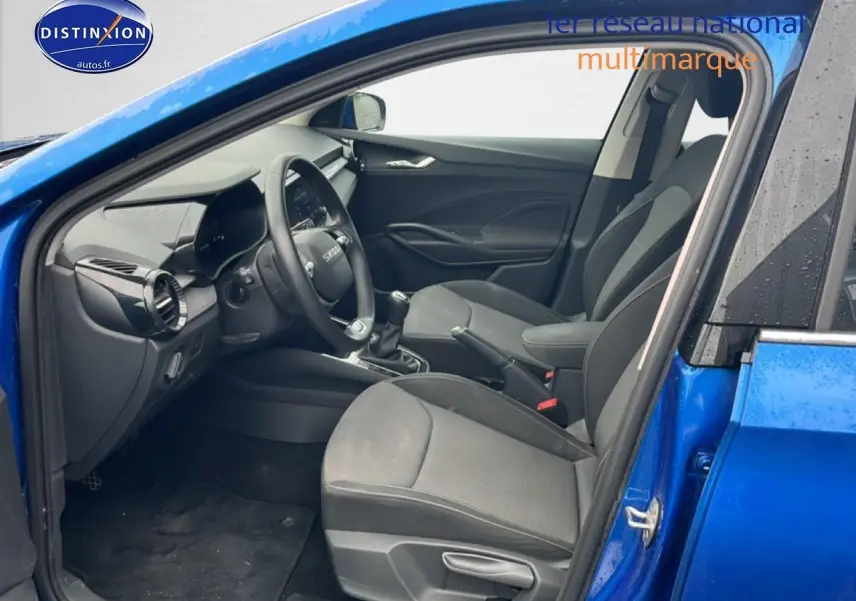 Intérieur avant droit de la Skoda Fabia bleu 2025, montrant sièges noirs, volant cuir multifonction et levier de vitesse manuel.