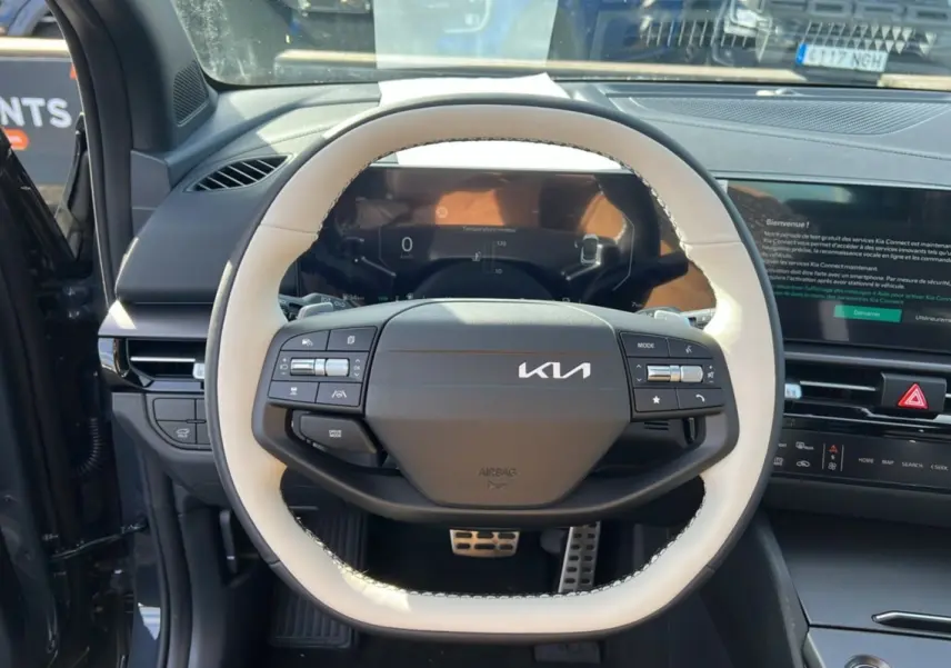 Vue rapprochée du volant cuir blanc et noir du Kia Sportage 2026 avec tableau de bord numérique et écran tactile.
