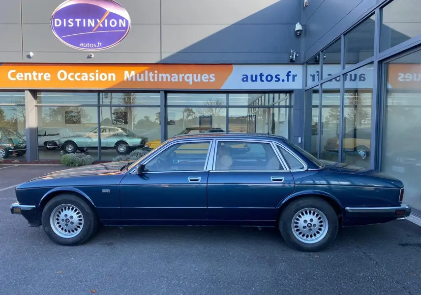 Profil côté gauche d'une Jaguar XJ6 3.6 Sovereign bleu foncé de 1987, berline classique aux jantes alliage d'origine.