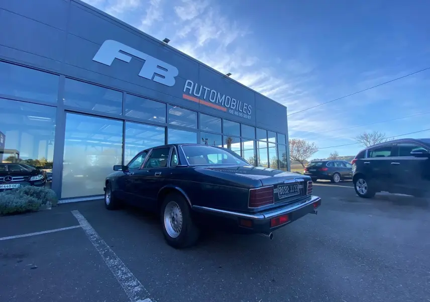 Jaguar XJ6 3.6 Sovereign bleu vue 3/4 arrière droit, stationnée devant un garage avec plaques françaises.