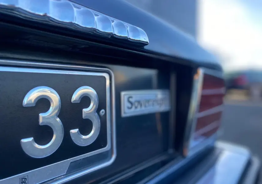 Gros plan sur l'arrière bleu d'une Jaguar XJ6 3.6 Sovereign de 1987, avec plaque et logo distinctifs visibles.