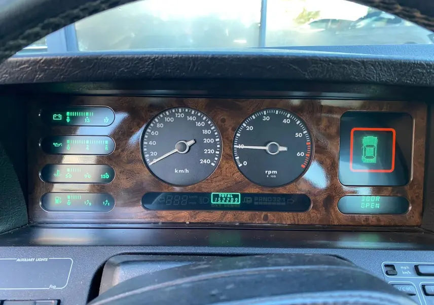 Tableau de bord en bois du Jaguar XJ6 3.6 Sovereign 1987, affichage digital et compteurs ronds vus de face.