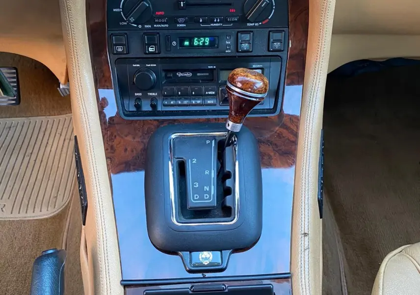 Gros plan sur la console centrale beige avec levier de vitesses boisée et tableau de bord en bois sur Jaguar XJ6 3.6 Sovereign 1987.