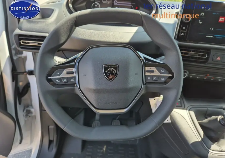 Vue plongeante sur le volant noir du Peugeot Partner 2025 avec tableau de bord et écran tactile visibles.