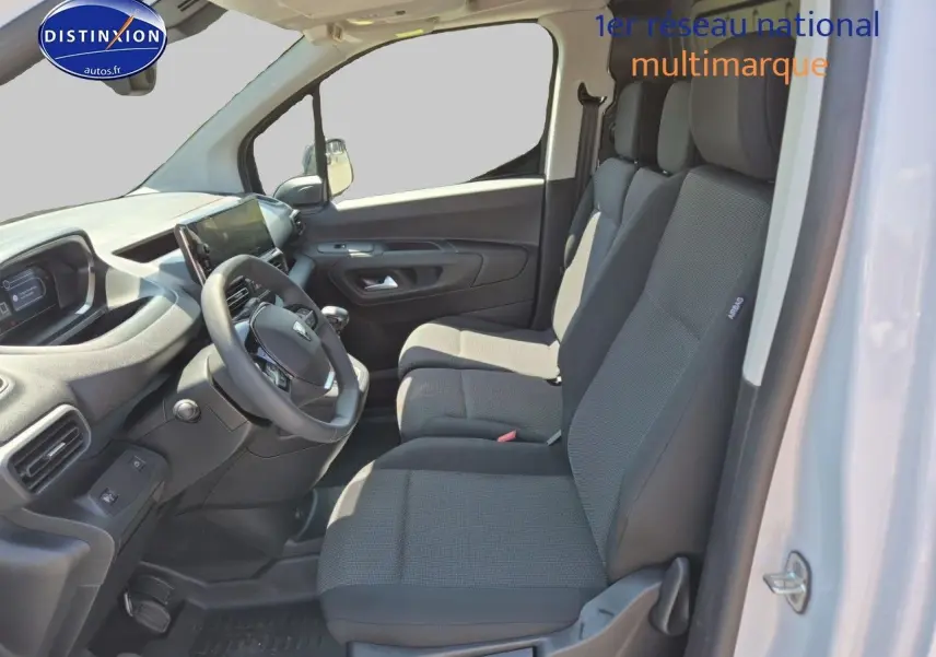 Intérieur du Peugeot Partner 2025 vu côté conducteur, sièges tissu gris et tableau de bord moderne noir.