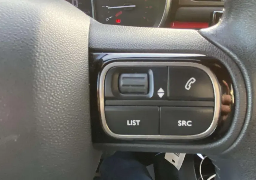 Gros plan sur les commandes audio au volant d'une Citroën C3 noire toit rouge, version Shine 2017.