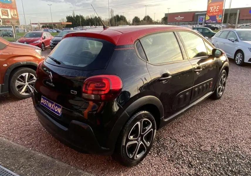 Vue 3/4 arrière droite d'une Citroën C3 noire avec toit rouge et protections latérales Airbump visibles.