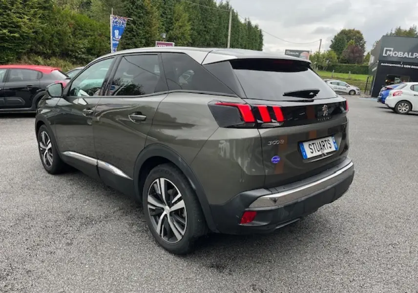 Peugeot 3008 gris Amazonite vue 3/4 arrière droit, jantes alliage et feux arrière à griffes rouges visibles.