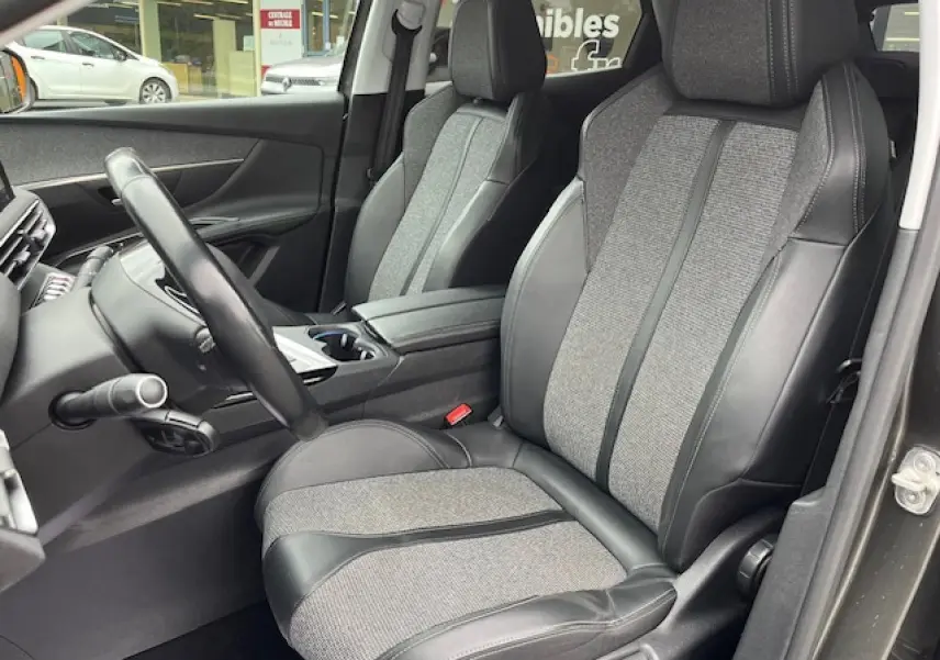 Intérieur du Peugeot 3008 2019, vue côté conducteur sur sièges semi-cuir gris et volant multifonctions.