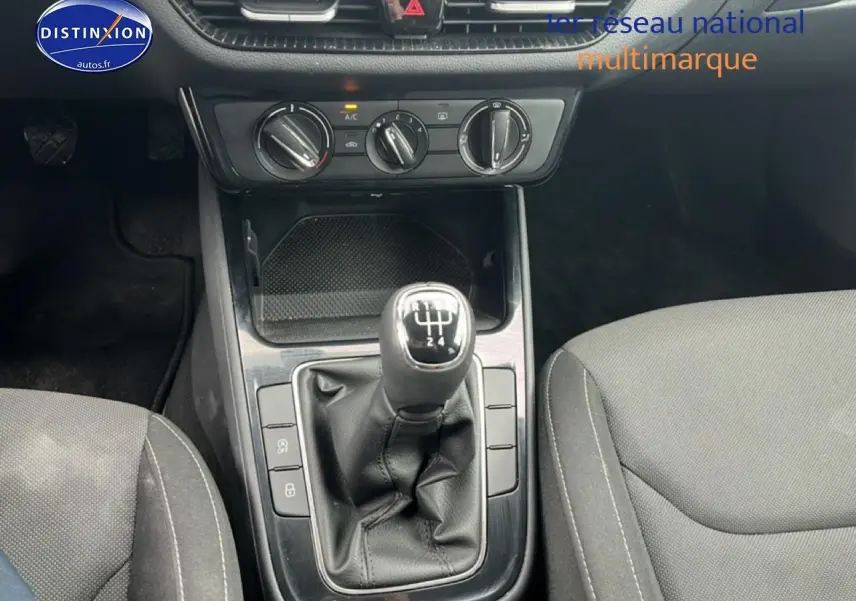 Gros plan sur la console centrale de la Skoda Fabia blanche, mettant en valeur le levier de vitesse manuel et les commandes de climatisation.
