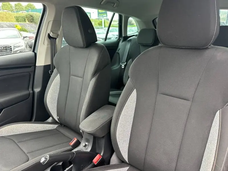 Vue intérieure rapprochée des sièges avant en tissu noir et gris d'une Skoda Scala 2025, avec accoudoir central.