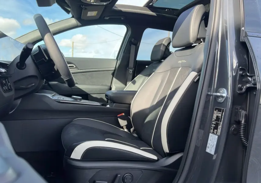 Vue intérieure côté conducteur du Kia Sportage gris eclipse avec sièges sport noirs et toit panoramique ouvert.