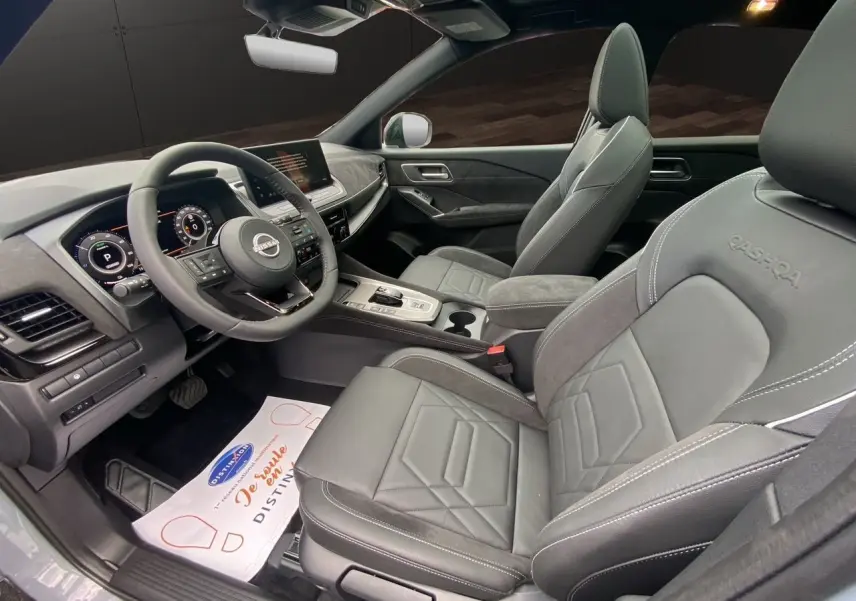 Intérieur du Nissan Qashqai 2025 en gris noir, vue côté conducteur, sièges cuir avec logo Qashqai brodé.