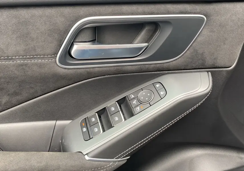 Gros plan sur la poignée intérieure et les commandes des vitres côté conducteur du Nissan Qashqai 2025 finition N-Design noir.