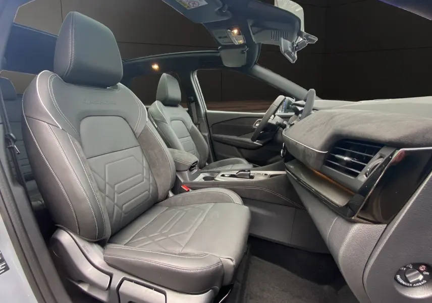 Vue intérieure côté conducteur du Nissan Qashqai 2025 avec sièges cuir gris et tableau de bord moderne.