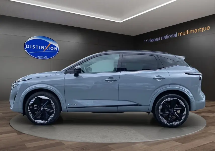 Profil côté gauche du Nissan Qashqai 1.5 e-POWER 190 BVA N-DESIGN gris ceramic avec toit noir en showroom.