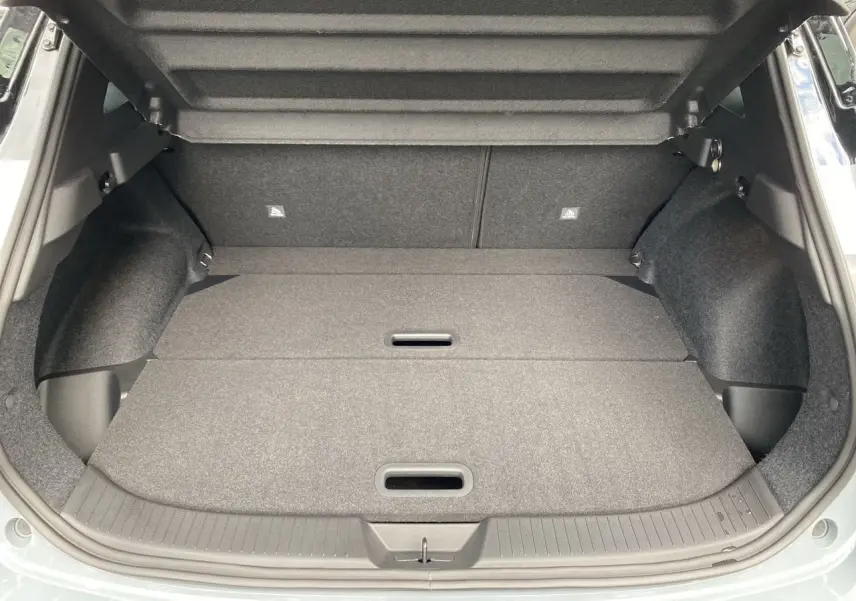 Coffre ouvert du Nissan Qashqai 2025 en gris ceramic et noir, montrant un espace de chargement plat et bien fini.