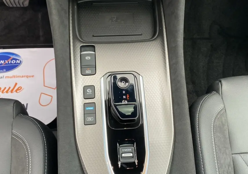 Vue plongeante sur la console centrale gris céramique du Nissan Qashqai 2025 avec levier de vitesses et boutons de contrôle.