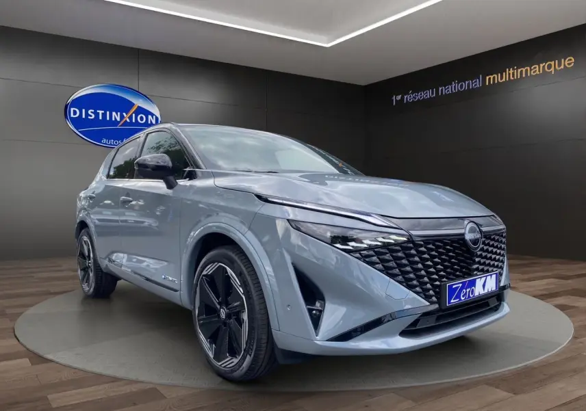 Nissan Qashqai 2025 gris ceramic et noir, vue 3/4 avant avec calandre noire et jantes noires distinctives.