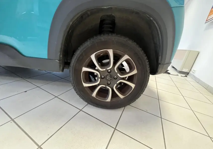 Gros plan sur la roue arrière droite d'une Citroën E-MEHARI cabriolet bleu clair avec jante alliage 15 pouces.