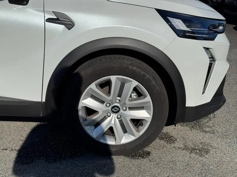Gros plan sur la roue avant droite et le pare-chocs avant blanc du Renault Captur 2025 avec jante alu et éclairage LED.