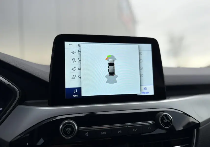 Écran tactile central du Ford Kuga 2024 affichant l'aide au stationnement avec vue de dessus du véhicule.