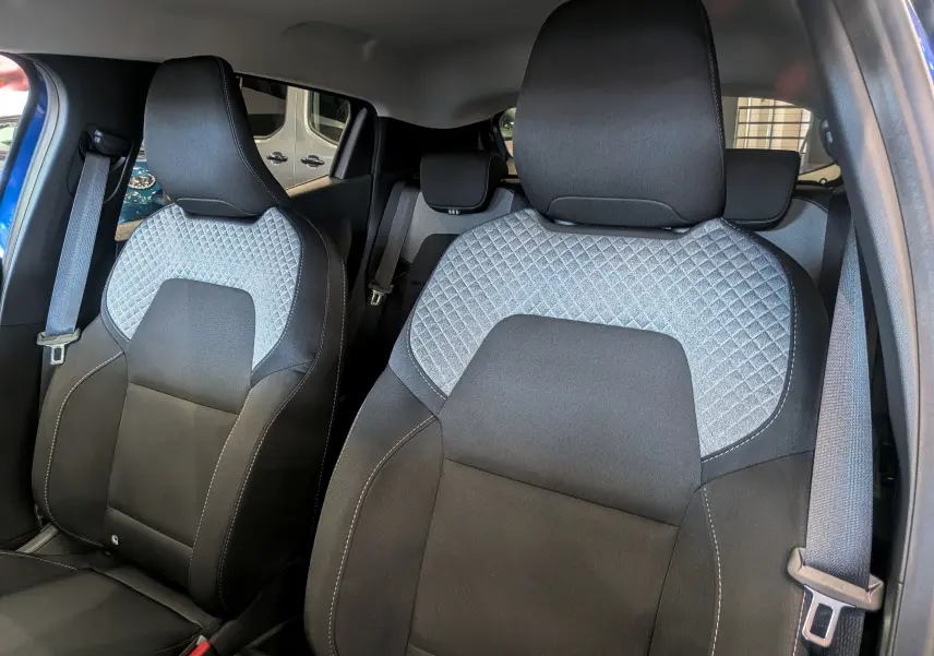 Vue intérieure rapprochée des sièges avant en tissu noir et gris avec surpiqûres de la Renault Clio V Bleu Iron 2025.
