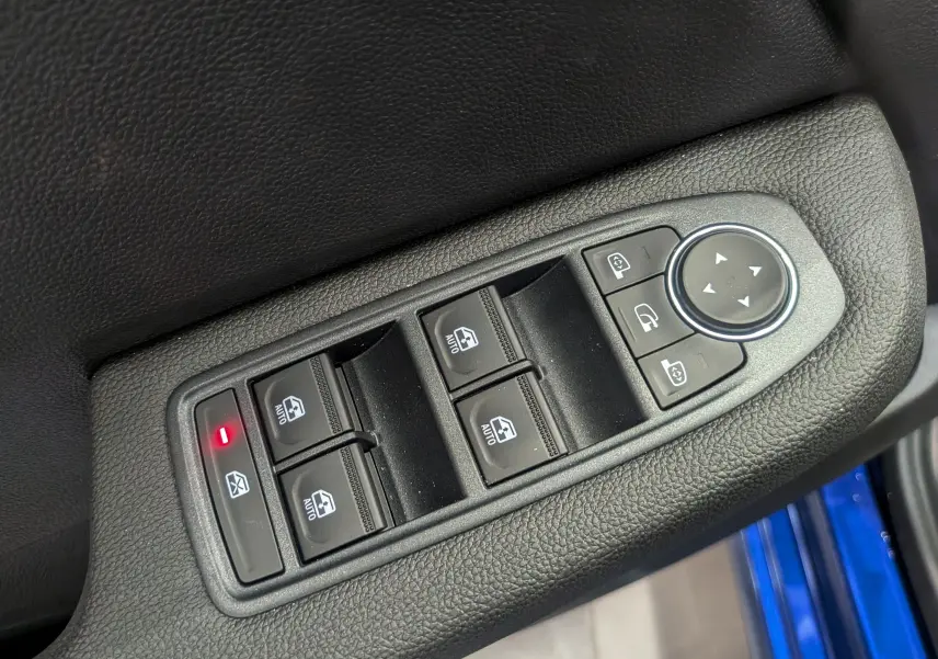 Gros plan sur les commandes de lève-vitres et rétroviseurs côté conducteur d’une Renault Clio V Bleu Iron, intérieur noir.