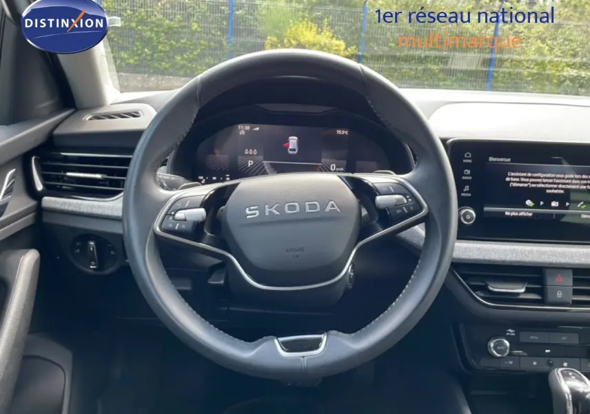Vue intérieure centrée sur le volant SKODA noir avec tableau de bord digital et écran tactile du SCALA blanc glacier.