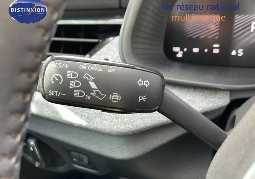Gros plan sur la commande de régulateur de vitesse au volant d'une Skoda Scala blanche Glacier, intérieur gris noir.