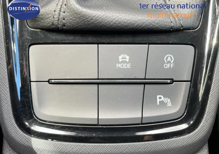Gros plan sur les boutons de commande du mode de conduite et du stationnement assisté dans une Skoda Scala blanche Glacier 2025.