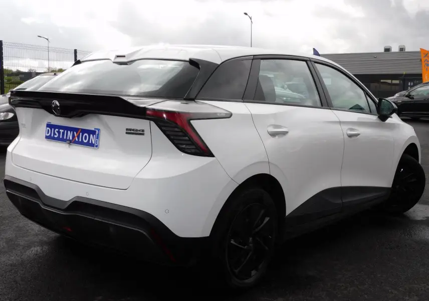 Vue 3/4 arrière droite d'une MG4 électrique blanche avec feux arrière LED et toit noir contrasté.