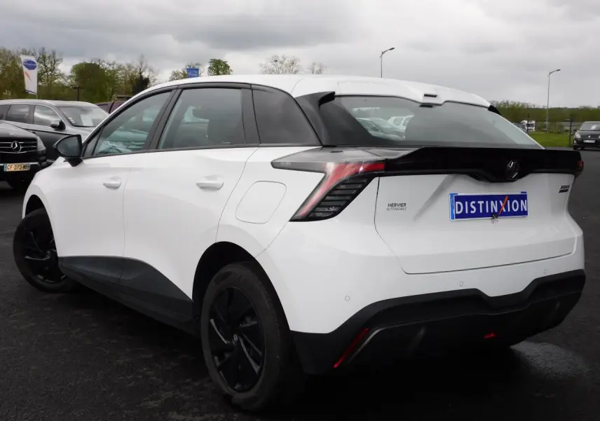 Vue 3/4 arrière droite d'une MG4 électrique blanche avec jantes noires et feux arrière LED distinctifs.