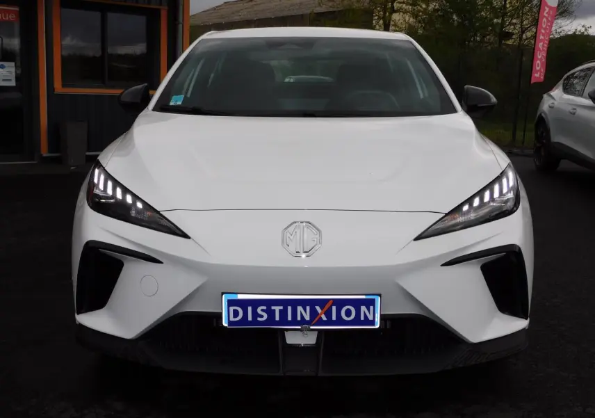 Vue de face du MG4 blanc électrique avec ses phares LED allumés et calandre épurée.