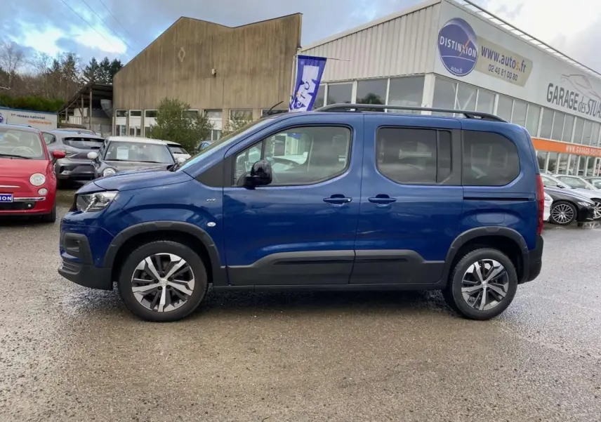 Profil côté gauche d'un Peugeot Rifter GT bleu métallisé 2023 avec jantes alliage et protections noires.