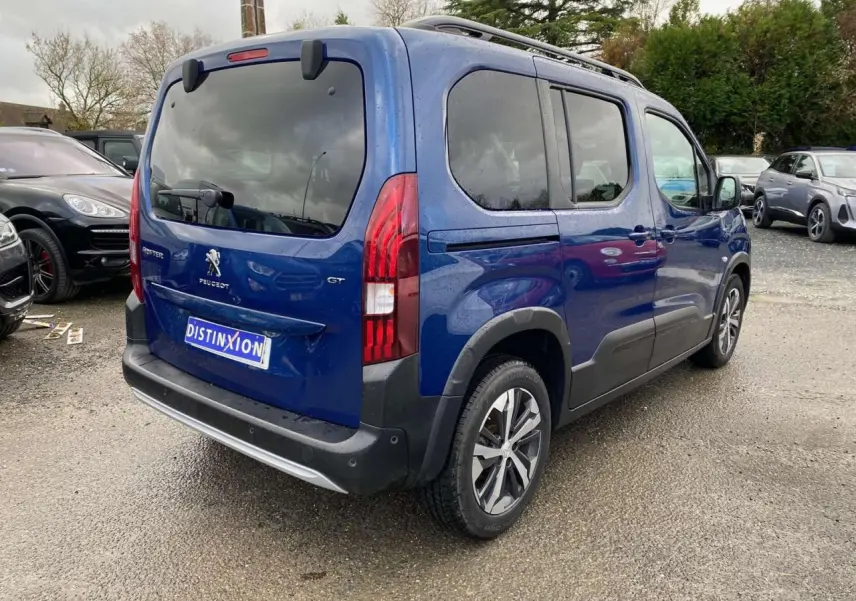 Vue 3/4 arrière droite d'un Peugeot Rifter GT bleu métallisé avec jantes alliage 17 pouces et vitres surteintées.