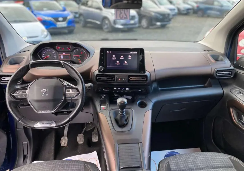 Vue intérieure avant du Peugeot Rifter GT bleu 2023, avec tableau de bord moderne et boîte manuelle.