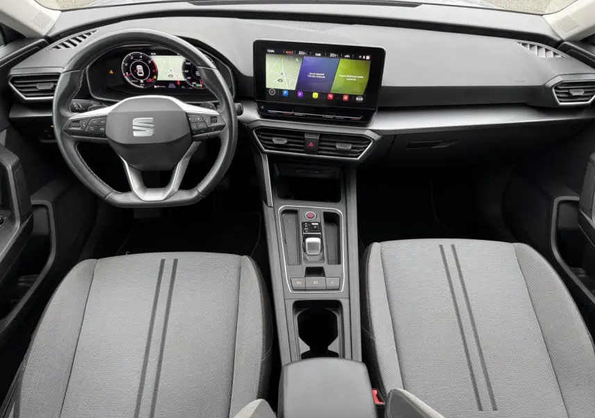 Intérieur de la SEAT Leon 2022 vu de dessus, avec tableau de bord digital et sièges gris clair à rayures.
