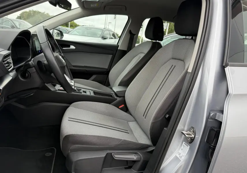 Intérieur côté conducteur d'une SEAT LEON 2022 argent Urban, avec sièges tissu gris et volant cuir multifonction.