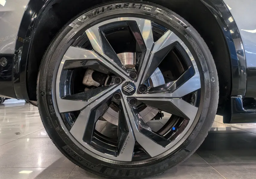 Gros plan sur la roue avant droite du Renault Austral E-Tech hybrid 200 Iconic esprit Alpine, jante biton noire et argent.