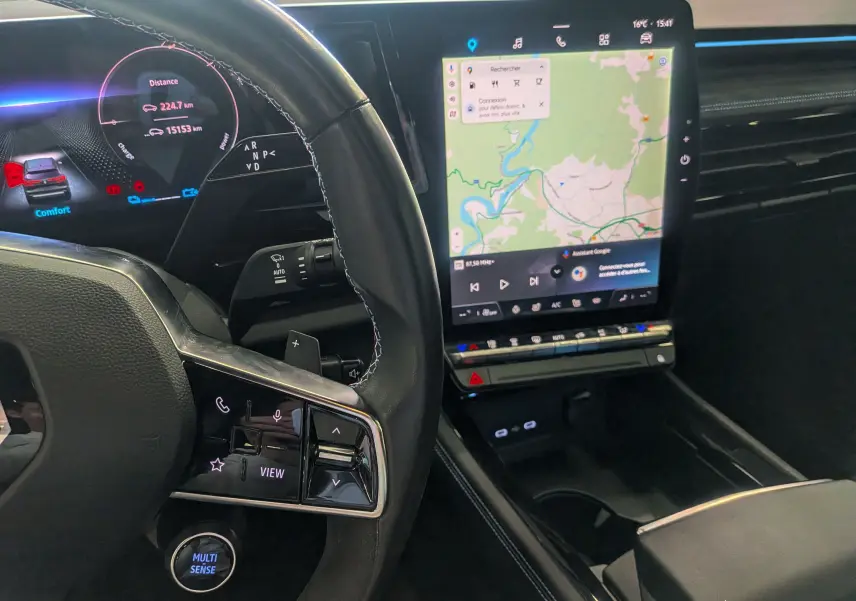 Vue intérieure du tableau de bord et écran tactile vertical du Renault Austral E-Tech hybrid 200 Iconic esprit Alpine, avec volant partiel visible.