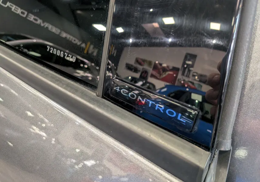 Détail du montant de porte arrière gauche gris schiste du Renault Austral E-Tech avec inscription 4CONTROL sur vitre noire.