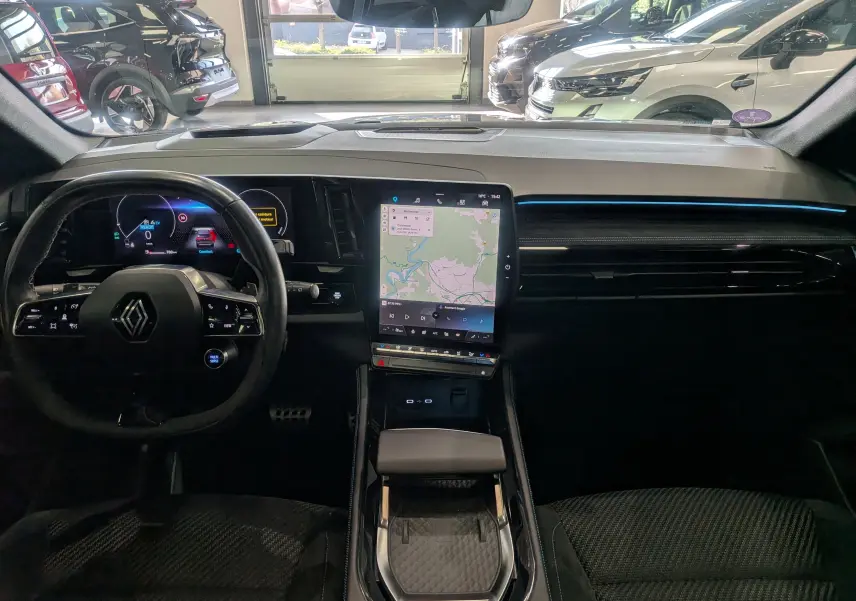 Vue intérieure avant du Renault Austral E-Tech hybride 2023, tableau de bord noir avec écran tactile central vertical et volant multifonction.